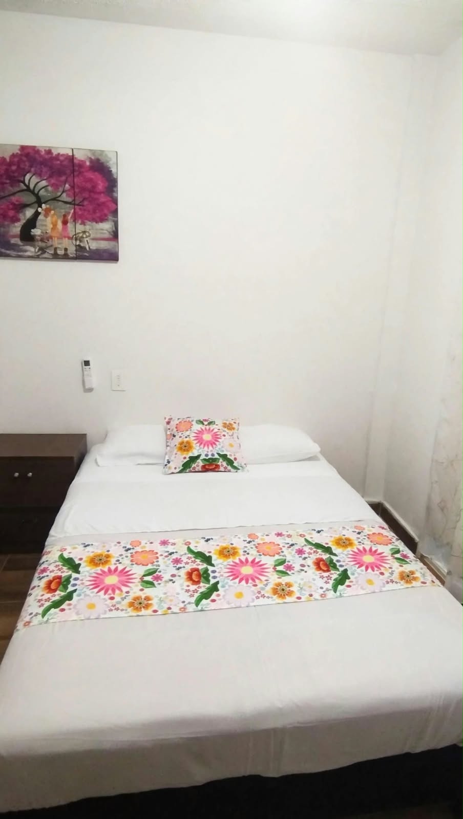 Vista de una habitaci&oacute;n con cama y ropa de cama floral.