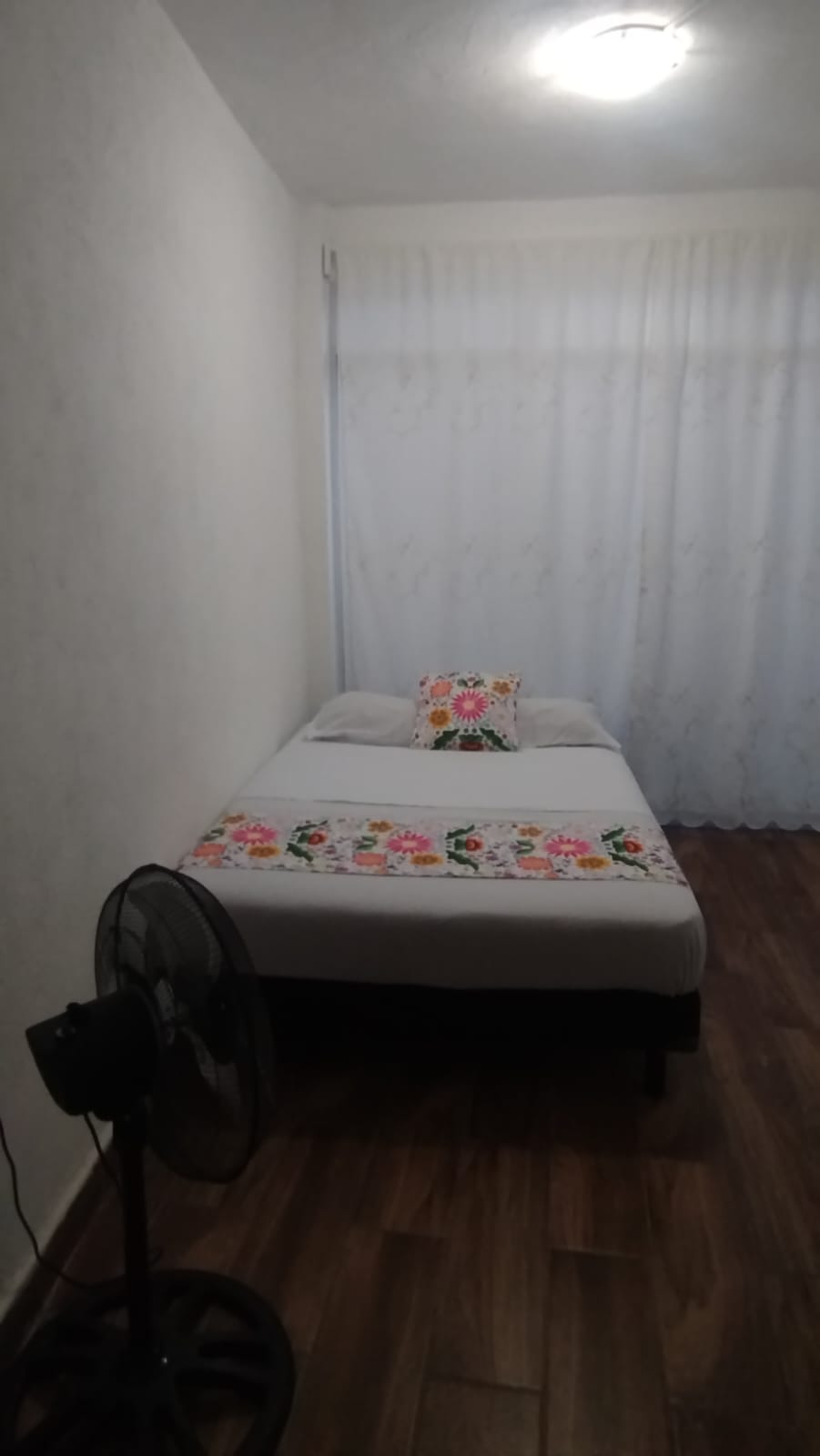 Fotograf&iacute;a de habitaci&oacute;n con cama y ventilador de piso.